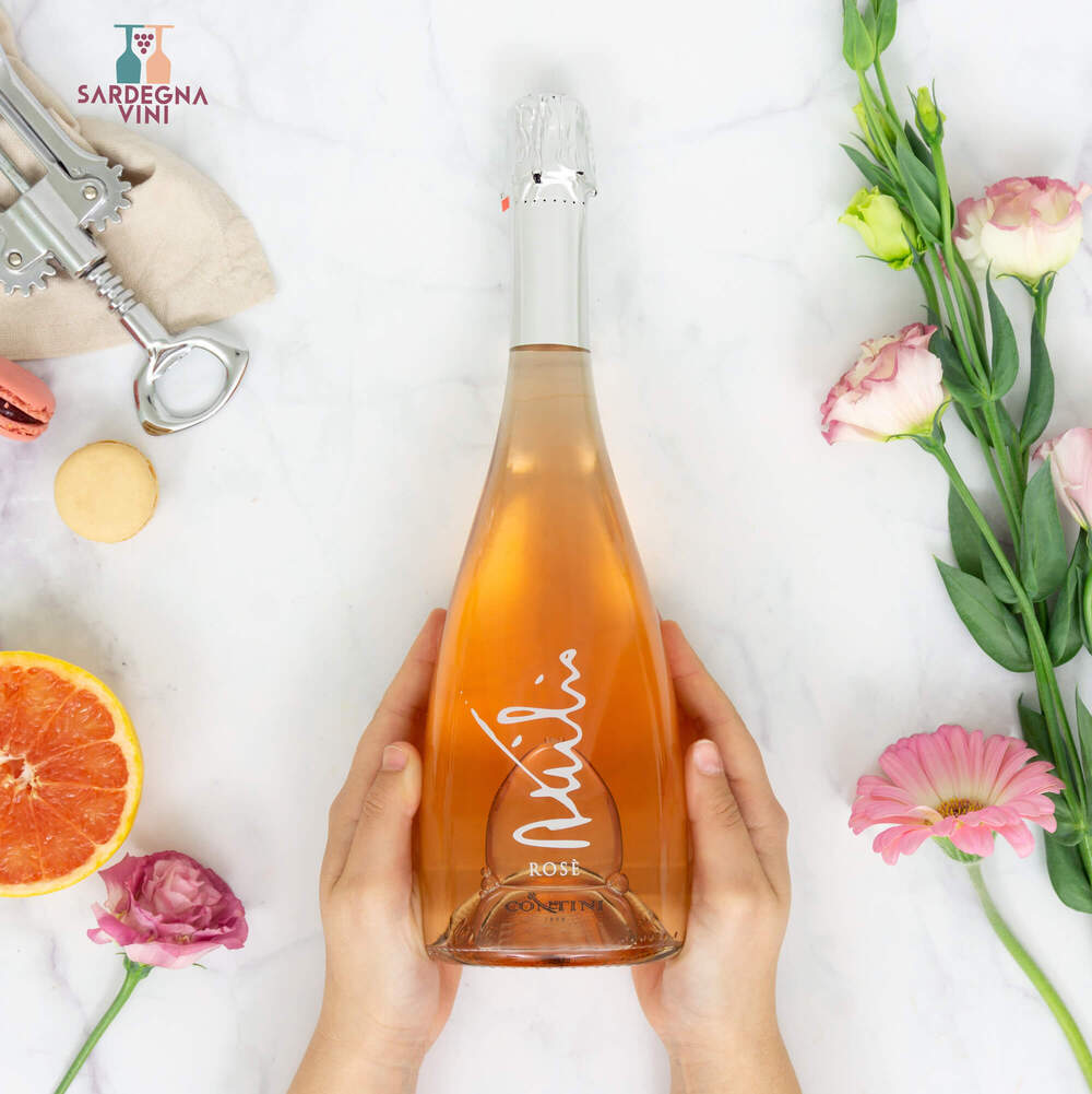 Attilio Spumante Brut Rosé by Cantina Contini in a glass with bubbles and a pink hue, set against a blurred background.