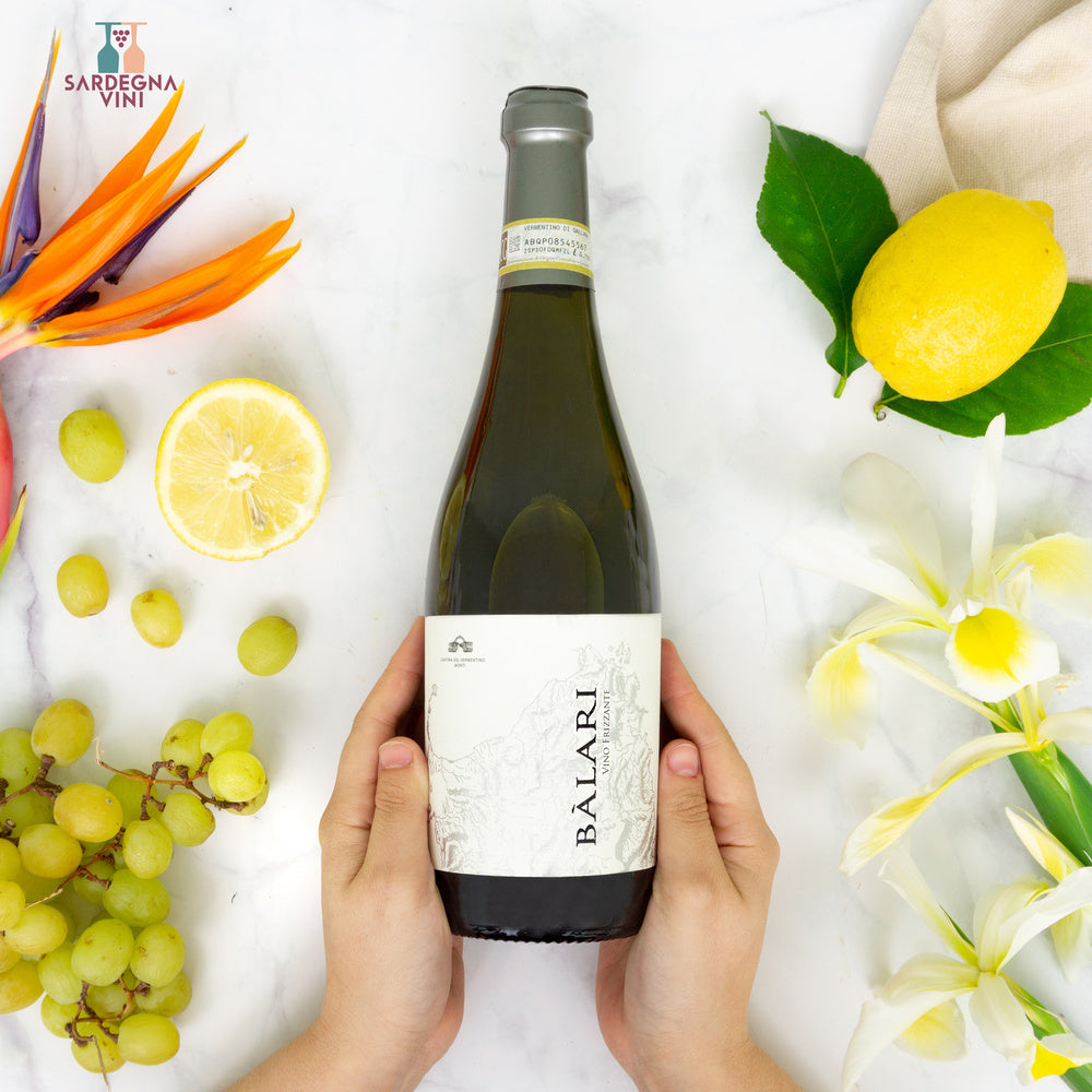 Bottle of Balari Frizzante Vermentino di Gallura DOCG by Cantina del Vermentino with bubbly white wine in a glass.