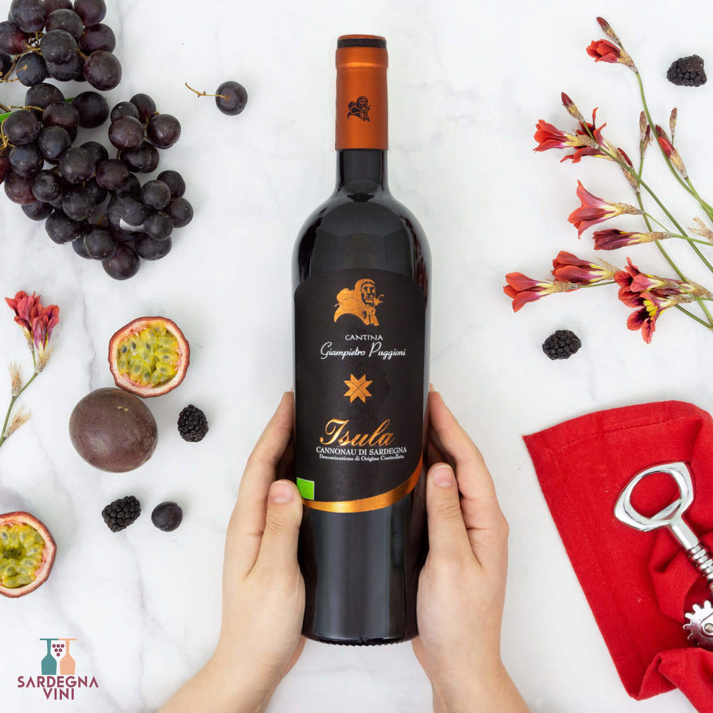 Bottle of Isula Cannonau di Sardegna BIO 2024, a red organic wine by Cantina Giampietro Puggioni, on a wooden table.